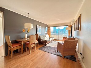 Ein modernes Wohnzimmer mit Essbereich, großen Fenstern und Blick auf die Stadt.