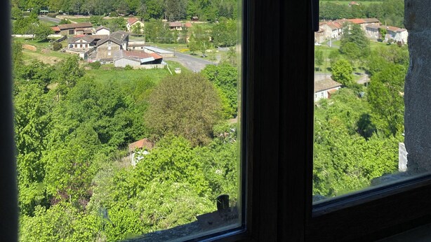A view through a window of a rural landscape with fields, trees, and a few buildings. - Movies and board games, quiet accommodation (Arlanc)