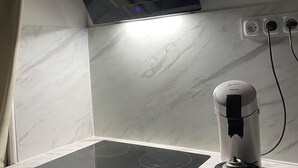 A kitchen with a black induction cooktop, a white countertop, a black range hood, and a white appliance on the counter. - Movies and board games, quiet accommodation (Arlanc)