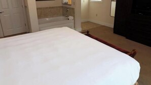 A bedroom with a bed, a bathtub, a mirror, and a TV. - 1 BR King with spa tub. Close to local attractions.Perfect for 250 celebration! (Williamsburg)