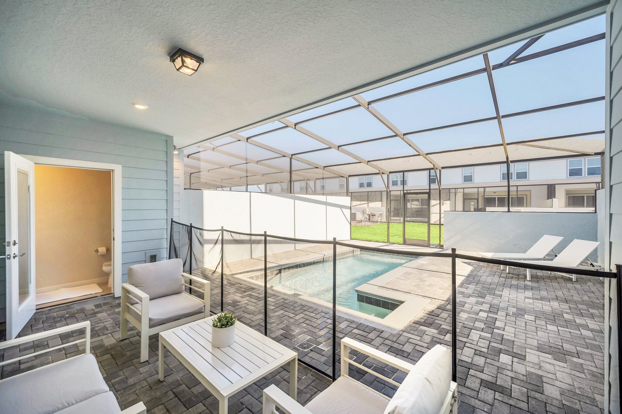 Un espacio al aire libre cubierto con piscina, sillones de descanso y una mesa de patio.