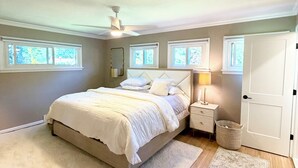 A bedroom with a bed, nightstands, a lamp, a ceiling fan, and a door. - Clean and Convenient 4-bedroom house in Pittsford! (Pittsford)