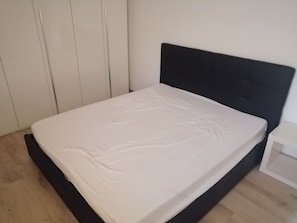 Ein Schlafzimmer mit einem Bett, einem Kleiderschrank und einem Nachttisch.