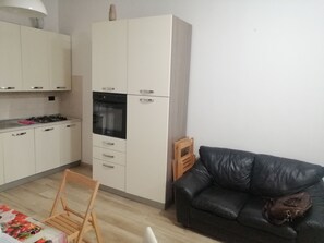 Eine moderne Küche mit weißen Schränken, einem schwarzen Backofen und einem Essbereich mit Holzstuhl und Tisch.