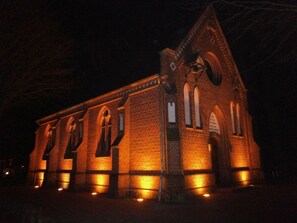 A brick building with arched windows and a triangular roof, illuminated at night. - Large Baltic Sea Nest (Boltenhagen)