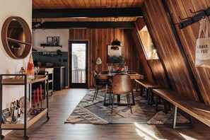 Ein Essbereich mit Holztisch, Stühlen und einer Bank. Eine Hängelampe hängt über dem Tisch und an der Wand befindet sich ein Spiegel.