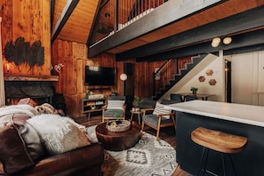 A rustic interior with a wooden staircase, a bar area, and a cozy seating arrangement. - Firefly Cabin with Mountain View (Big Bear Lake)
