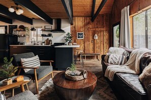 A cozy living room with a sofa, a coffee table, and a chair. - Firefly Cabin with Mountain View (Big Bear Lake)