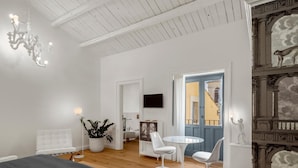 A room with a bed, a round table with chairs, a potted plant, and a TV on the wall. - Carla, elegant and romantic studio suite on the 2nd floor in the city of Noto (NOTO)