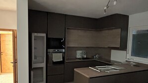 Una cocina moderna con electrodomésticos integrados, piso de madera y una ventana con persianas.