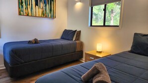 Un dormitorio con dos camas, una mesita de noche, una lámpara de pared y un cuadro.