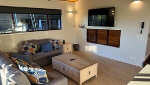 Una sala de estar moderna con sofá, mesa de centro y televisor montado en la pared.