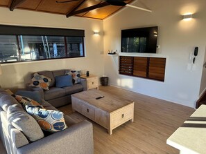 A modern living room with a sofa, coffee table, and a TV mounted on the wall.