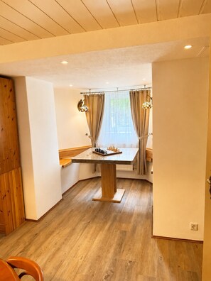 A dining area with a wooden table, curtains, and a chessboard. - Villa on Lake Wangermeer—North Sea Vacation, Terrace, Dog-Friendly, Up to 5 Guests (Wangerland)
