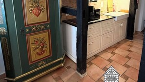 Eine Küche mit einem grünen Schrank, weißen Schränken und einem gefliesten Boden.