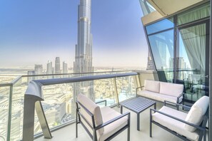 Ein Balkon mit Blick auf eine Skyline, darunter ein hoher Wolkenkratzer. Zwei weiße Sofas und ein kleiner Tisch sind vorhanden.
