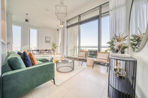 Ein modernes Wohnzimmer mit einem grünen Sofa, einem runden Couchtisch und einem großen Fenster mit Blick.