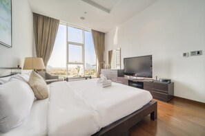 Una habitación de hotel moderna con una cama grande, un televisor de pantalla plana, un escritorio con una computadora y vista a la ciudad.