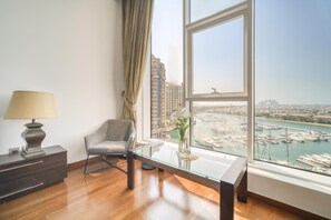 Habitación moderna con una mesa de vidrio, una silla, una lámpara y vistas a un puerto deportivo a través de amplias ventanas.