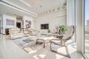 Eine geräumige Lobby mit Ledersofas, einem großen Teppich und einem Fernseher.