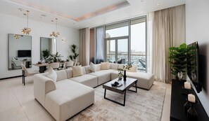 Ein modernes Wohnzimmer mit einem Ecksofa, einem Essbereich und einem großen Fenster mit Blick auf die Stadt.