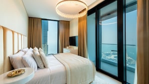 A modern hotel room with a large bed, a bedside table, a nightstand, and a view of a cityscape through floor-to-ceiling windows. - Gorgeous Apt wz Stunning Sea Views in Address JBR (Dubai)