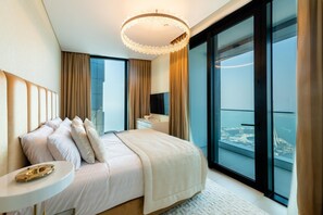 Una habitación de hotel moderna con una cama grande, una mesita de noche y vistas a un paisaje urbano a través de ventanales del suelo al techo.