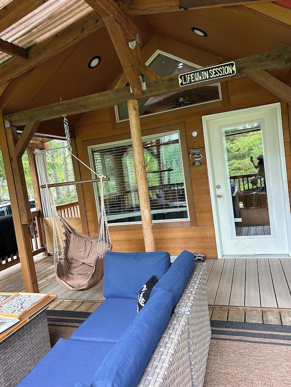 A wooden deck with a hammock, a blue sofa, and a sign that reads 'LIFE IS IN SESSION.' - Cozy Woodland Escape in Hoodsport near Lake Kokanee and Olympic Hiking (Hoodsport)