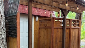 Een houten terras met een pergola, een rode deur en een houten omheining.
