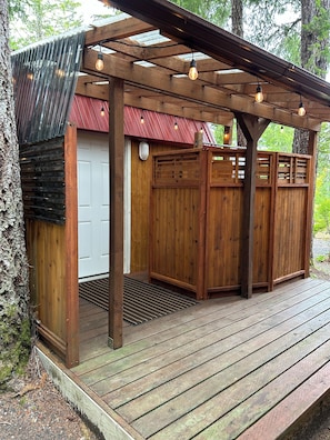 A wooden deck with a pergola, a red door, and a wooden fence. - Cozy Woodland Escape in Hoodsport near Lake Kokanee and Olympic Hiking (Hoodsport)