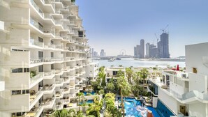 Ein Hochhaus-Hotel mit mehreren Balkonen, einem Schwimmbad und Blick auf die Stadtlandschaft und das Wasser.