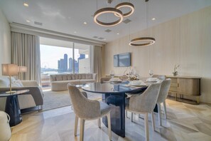 A modern hotel room with a large window, a dining area with a round table, and a sofa. - Modern Sea View Apt. at the FIVE Palm Jumeirah (Dubai)