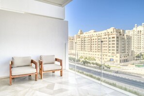A balcony with two wooden chairs and a view of a large building complex. - Modern Sea View Apt. at the FIVE Palm Jumeirah (Dubai)