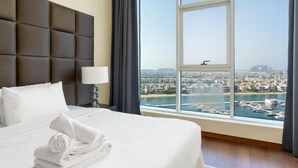 Une chambre d’hôtel dotée d’un grand lit, offrant une vue sur le paysage urbain et l’eau, et agrémentée d’une tête de lit moderne.