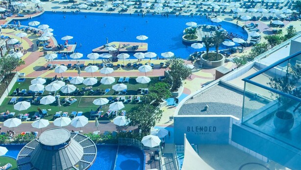 Un complexe hôtelier doté de plusieurs piscines, de chaises longues et de parasols.