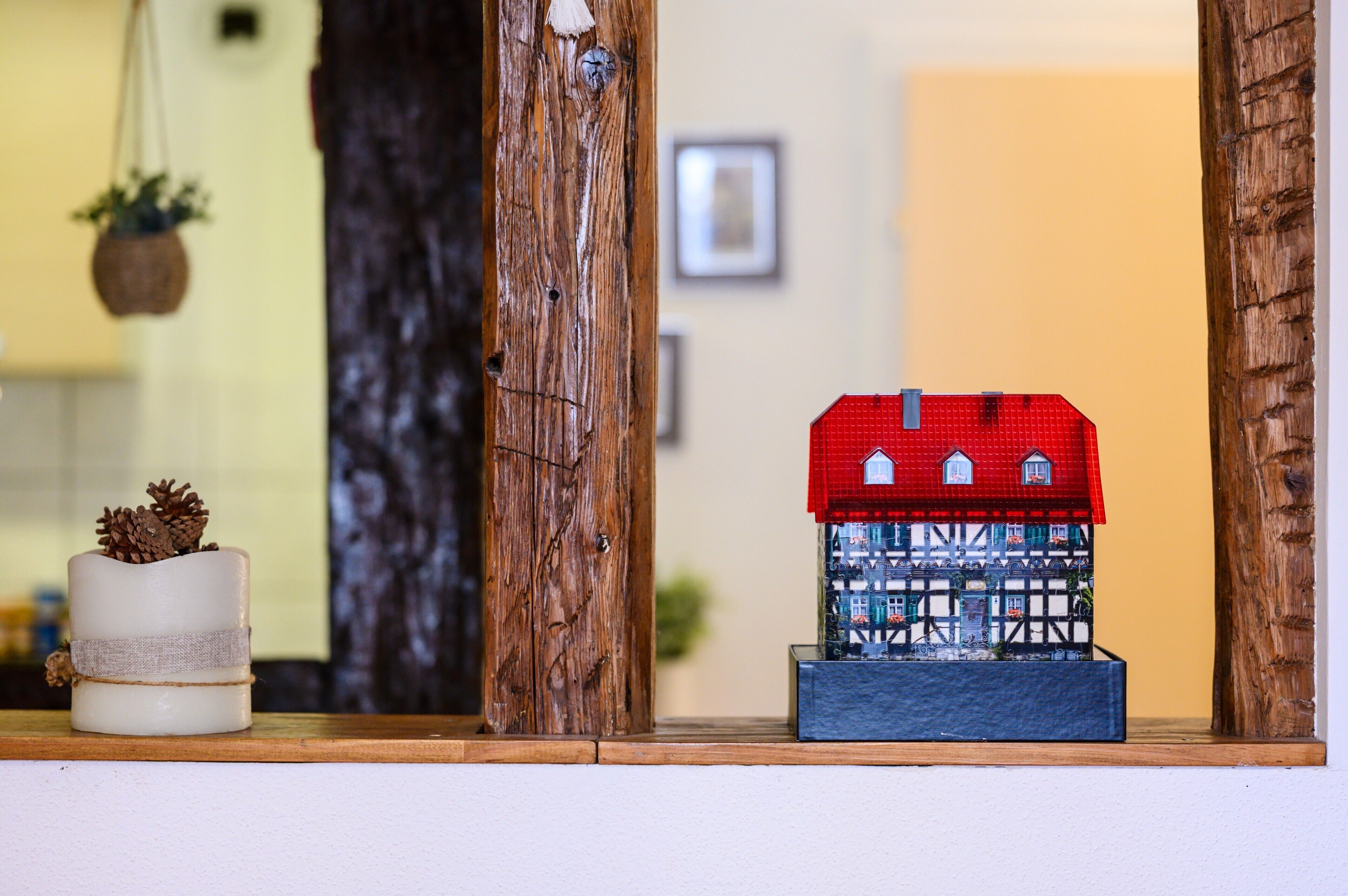 Una casa modelo con techo rojo y paredes blancas, colocada sobre una estantería.