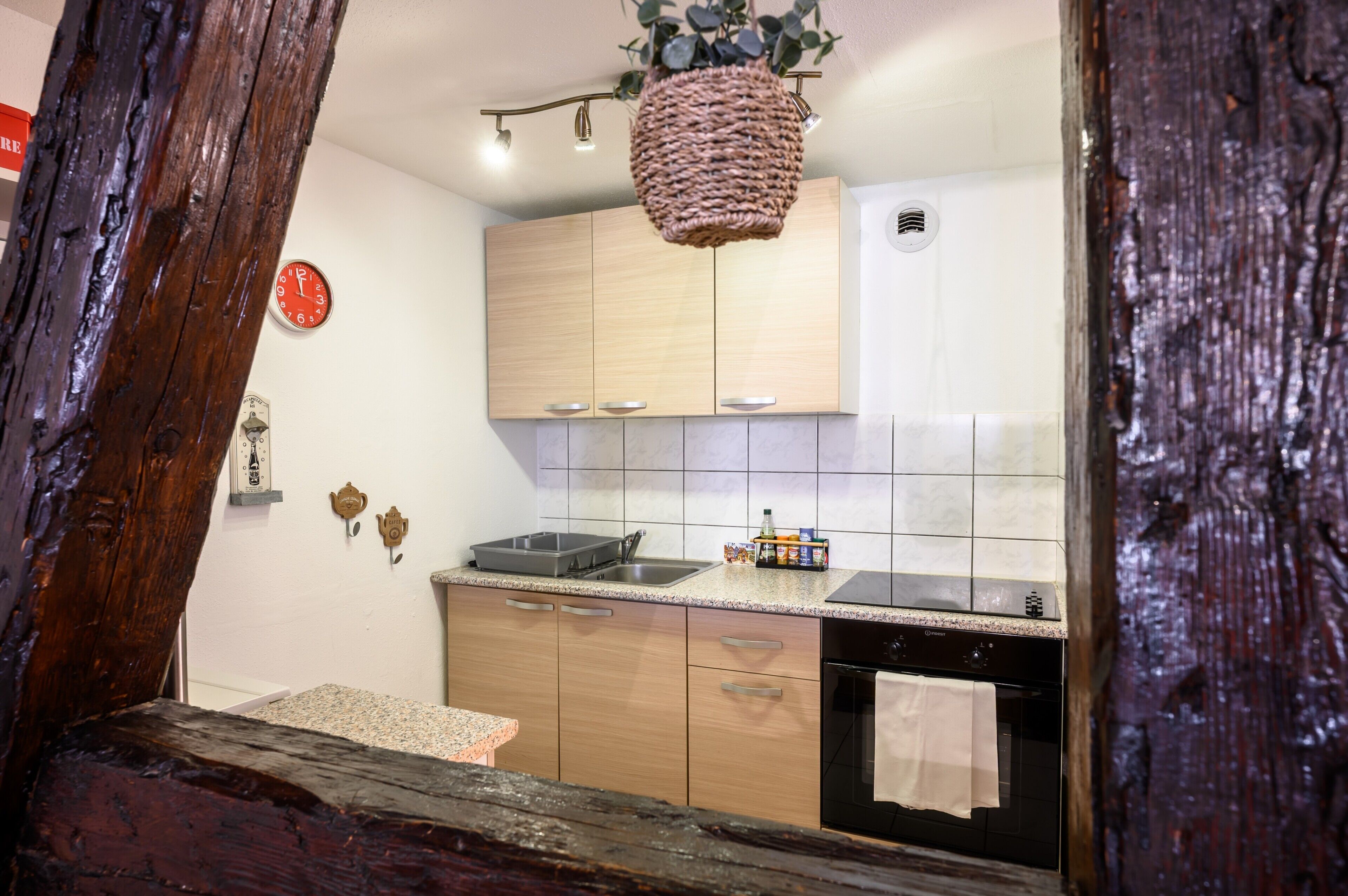 Eine Küche mit Holzschränken, einer Granit-Arbeitsplatte, einem Pendelkorb, einer Uhr und einem Handtuch, das an der Backofentür hängt.