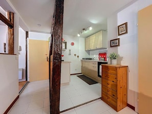 Una cocina con armarios blancos, un mueble de madera, un electrodoméstico rojo y un reloj en la pared.