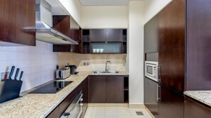 Eine moderne Küche mit dunklen Holzschränken, einer Edelstahl-Dunstabzugshaube, einer Mikrowelle und einem eingebauten Backofen.