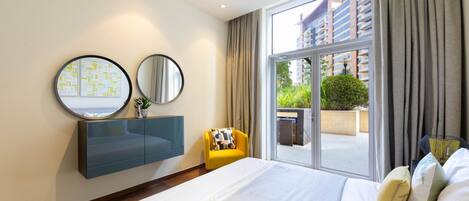 A hotel room with a bed, a blue cabinet, two round mirrors, a yellow chair, and a large window with curtains.