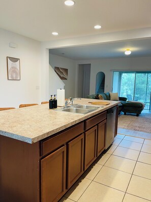 Una cocina con una isla grande, un fregadero y una zona de comedor con sillas.