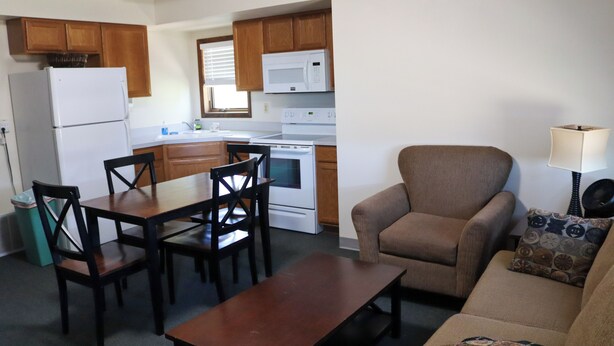 A compact living space with a kitchenette, a dining area with a table and chairs, a sofa, and a lamp. - Cozy Two-Bedroom Apartment at Sullivan Hills/Private Pond & 640 Acres to Explore (Lodgepole)