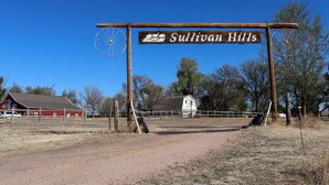 A rural road sign for Sullivan Hills with a wooden post and a metal wheel. - Cozy Two-Bedroom Apartment at Sullivan Hills/Private Pond & 640 Acres to Explore (Lodgepole)