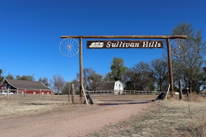 Un panneau de signalisation routière en milieu rural indiquant la direction de Sullivan Hills, avec un poteau en bois et une roue en métal.