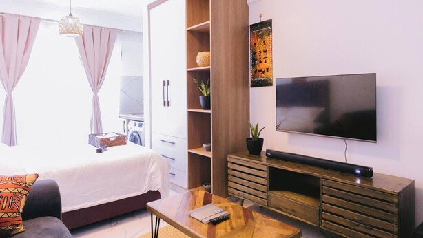 Un salon moderne avec un canapé, une table basse, un téléviseur et un meuble en bois.