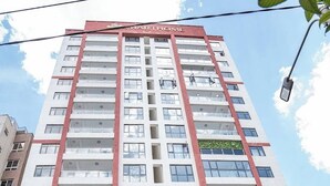 Un immeuble à plusieurs étages, doté d’une façade rouge et blanche bien visible, de balcons et d’une enseigne « SMARTHOME » clairement affichée.