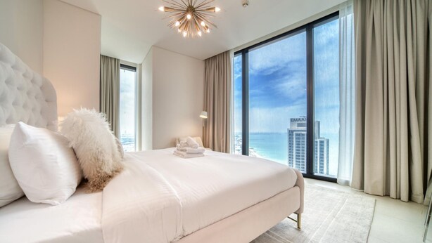 Une chambre d’hôtel moderne avec un grand lit, une vue sur la ville et une grande fenêtre.