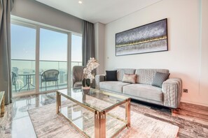 Una sala de estar moderna con una mesa de centro de vidrio, un sofá y un ventanal con vistas a la ciudad.