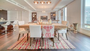 A modern dining area with a wooden table, white chairs, and a patterned rug. - Sleek and Convenient 1BR Apt in DIFC (Dubai)