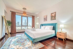 Ein Schlafzimmer mit einem großen Bett, Blick auf die Stadt, einem blauen Kopfteil und einem Nachttisch mit einer Lampe.